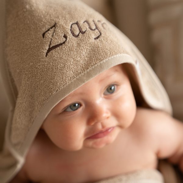 Baby in een beige badcape met naam