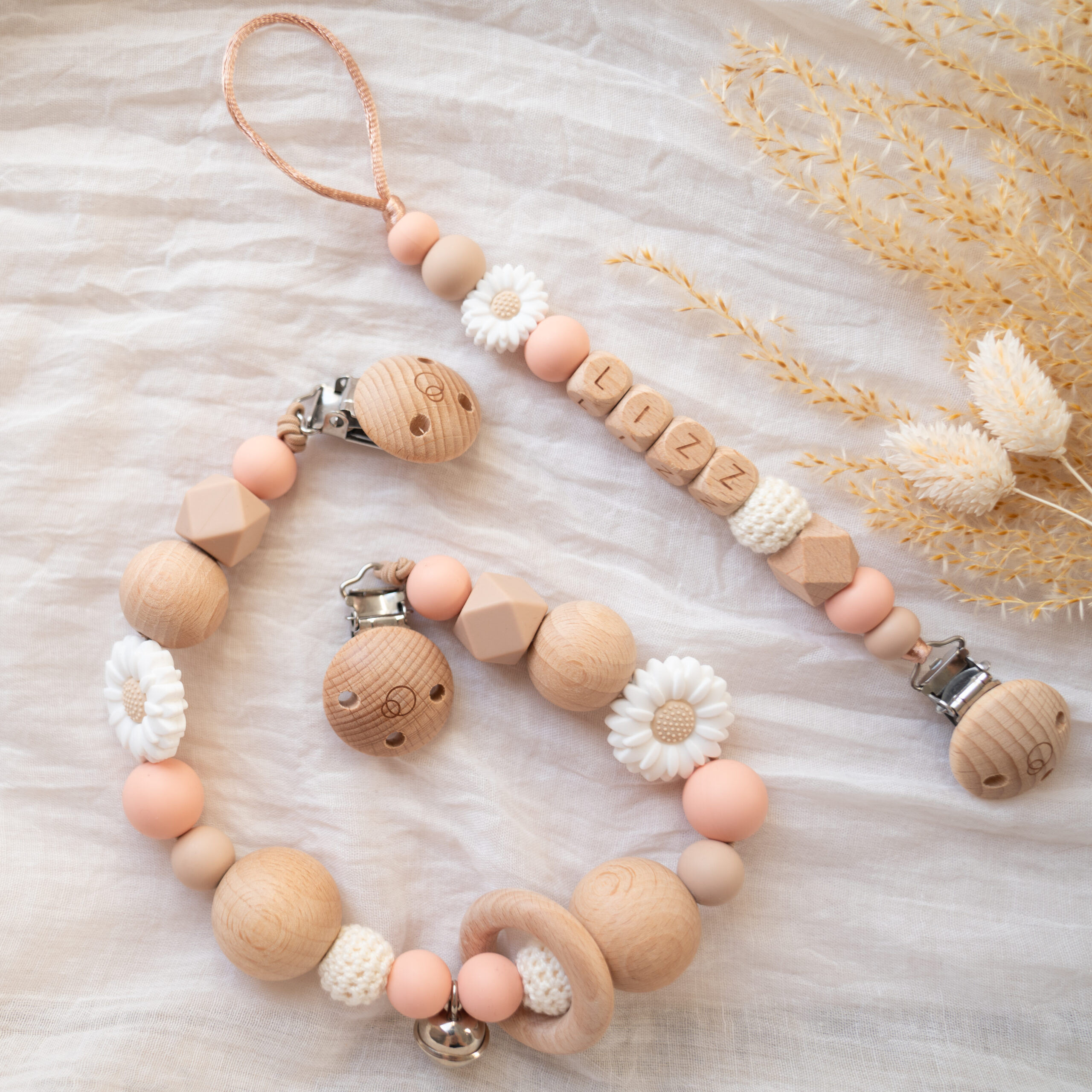 Giftset met naam met een speenkoord en wagenspanner in het zalm en witte bloem